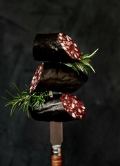 Black pudding or blood sausage with rosemary on a fork.