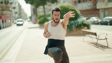 Young hispanic man karate fighter training at park