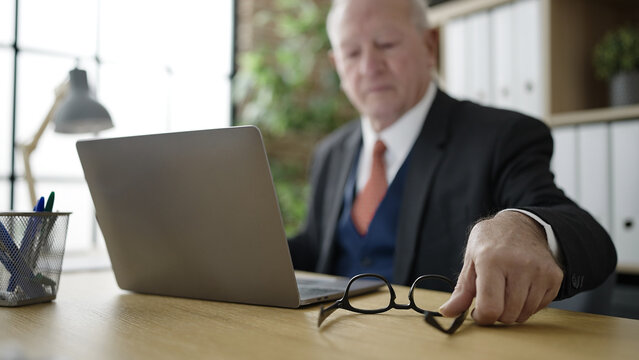 senior business worker holding glasses at office