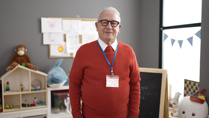 senior working as teacher smiling at kindergarten