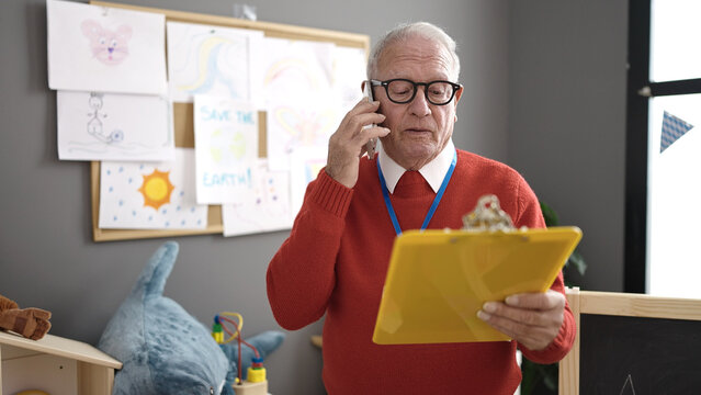 senior working as teacher writing on clipboard speaking on the telephone at kindergarten