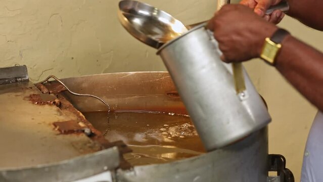 A worker takes a sample of lye solution and organic oil solution from a container