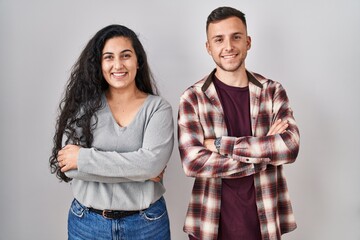 Young hispanic couple standing over white background happy face smiling with crossed arms looking at the camera. positive person.