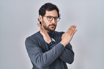 Obraz premium Handsome latin man standing over isolated background rejection expression crossing arms doing negative sign, angry face