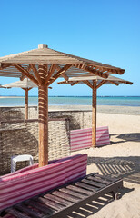 Wooden sun umbrellas, sun beds and windscreens on beach.
