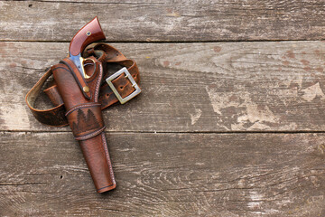 Black powder revolver in a leather holster with a leather belt on the background of old, worn...