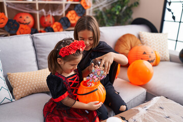 Fototapeta premium Adorable boy and girl having halloween party putting candies in pumpkin basket at home