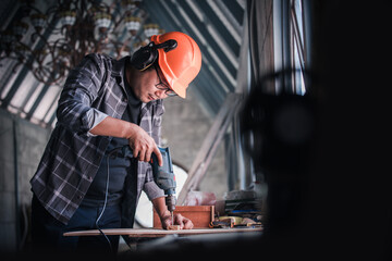 Skilled carpenter cutting a piece of wood in his woodwork workshop, using a hand saw, Pen, ruler, wood screw. Carpenter working on woodworking machines in carpentry shop. copy space for text.