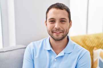 Fototapeta premium Young man smiling confident sitting on sofa at home