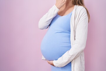 Young pregnant woman expecting a baby, touching pregnant belly covering mouth with hand, shocked...