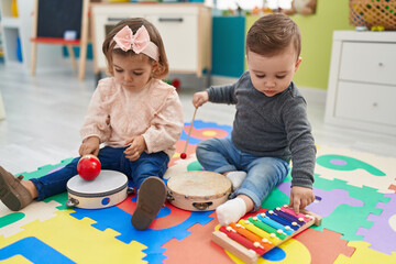 Adorable boy and girl playing xylophone and tambourine at kindergarten