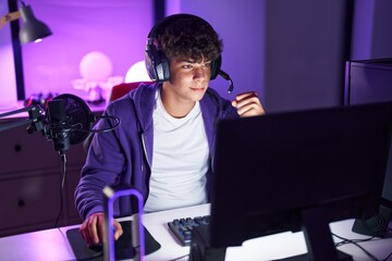 Young hispanic teenager streamer playing video game with winner expression at gaming room