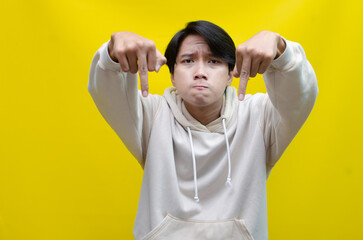 Asian young man showing his middle finger with a bad and angry expression isolated over a yellow...