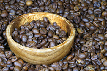 Coffee beans in a round wooden bowl close-up. Roasted aromatic coffee macro. Brown coffee background