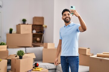 Fototapeta na wymiar Young hispanic man making selfie by the smartphone standing at new home
