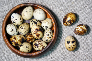 Quail eggs in a round wooden bowl on canvas, close-up, macro. Eggshell stains. Spotted pattern on the eggs. Dietary healthy foods. Egg