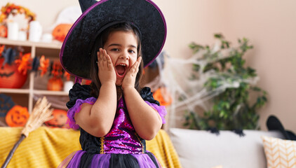 Adorable hispanic girl having halloween party with surprise expression at home
