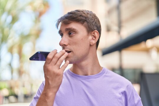 Young caucasian man talking on smartphone with serious expression at street