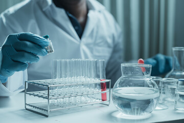 Scientist holding flask with lab glassware and chemistry laboratory test tubes Research and development in science laboratory, science technology concept
