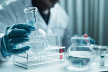 Scientist holding flask with lab glassware and chemistry laboratory test tubes Research and development in science laboratory, science technology concept
