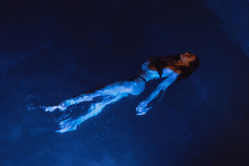 Swimmer woman in swimming pool at night on vacations, view from above