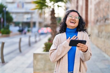 Young chinese woman smiling confident watching video on smartphone at street