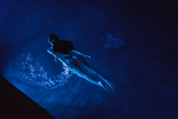 Swimmer woman in swimming pool at night on vacations, view from above
