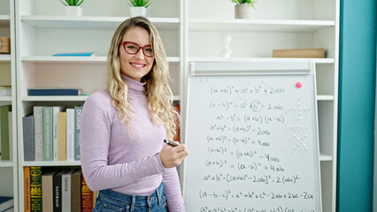 Young blonde woman teacher teaching maths lesson at classroom