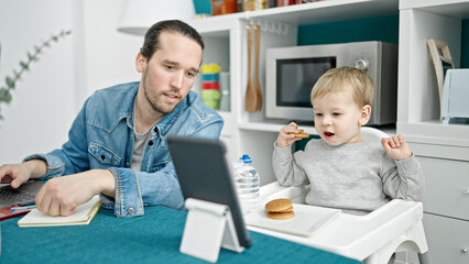 Father and son working and taking care child at dinning room