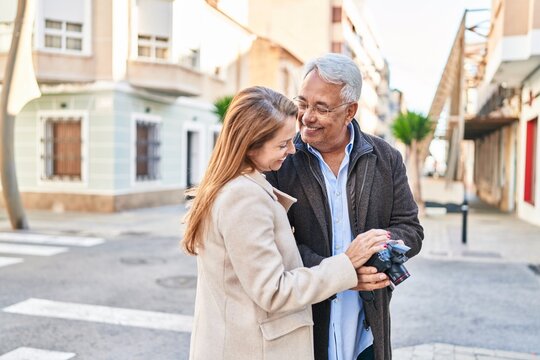 Middle age man and woman couple holding professional camera at street