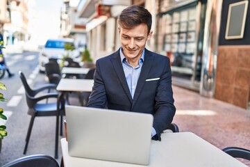 Young man business worker using laptop sitting on table at coffee shop terrace