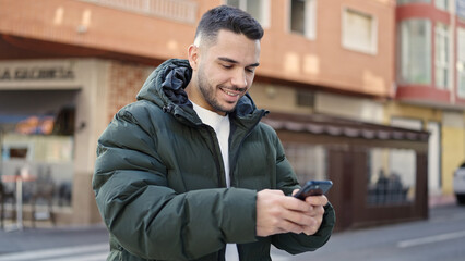 Fototapeta na wymiar Young hispanic man smiling confident using smartphone at coffee shop terrace