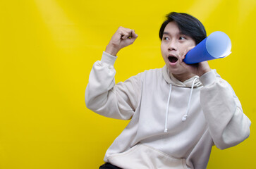 Euphoric and overjoyed asian man raising fist and holding paper megaphone giving announcement