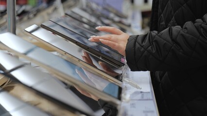 The girl buys a tablet. Shop of modern electronics. A woman chooses a tablet. Shop of modern technologies. Buying an e-book