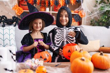 Adorable boy and girl having halloween party holding pumpkin basket at home