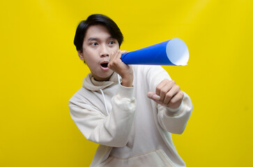 Euphoric and overjoyed asian man raising fist and holding paper megaphone giving announcement