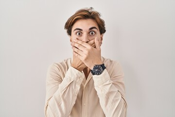 Young man standing over isolated background shocked covering mouth with hands for mistake. secret concept.