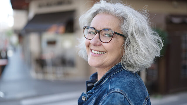 Middle age woman with grey hair smiling confident at street