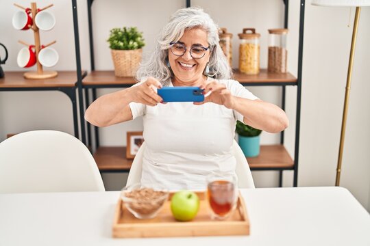 Middle age woman make photo to healthy breakfast at home