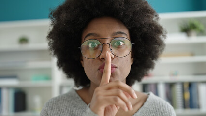 African american woman student doing silence gesture at library university