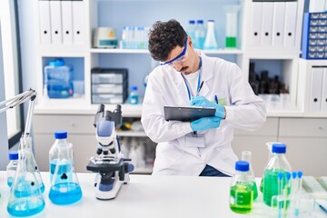 Young caucasian man scientist writing report working at laboratory