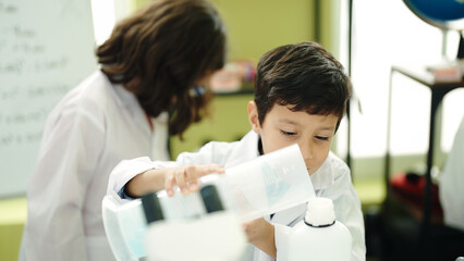 Adorable boy and girl student pouring liquid on test tube at laboratory classroom