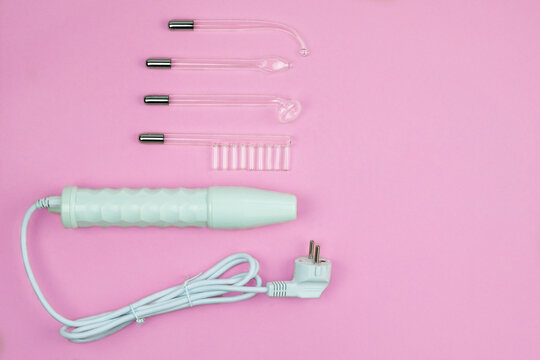 Darsonval for body and hair care on a pink background. Therapy for skin. Darsonvalization. Top view. Copy space.