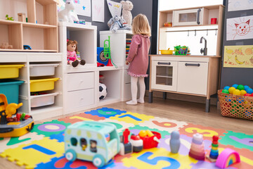 Adorable blonde girl playing with toys standing at kindergarten