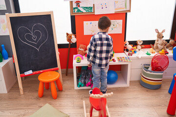 Adorable caucasian boy playing on back view at kindergarten