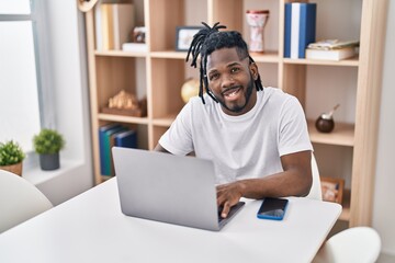 African american woman using laptop sitting on table at home