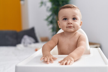 Adorable caucasian baby sitting on highchair at home