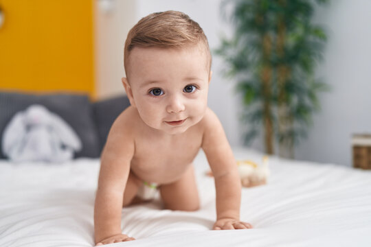 Adorable caucasian baby crawling on bed at bedroom