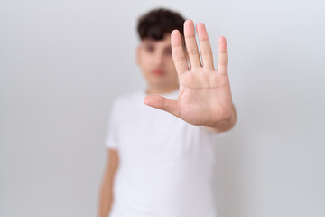 Young non binary man wearing casual white t shirt doing stop sing with palm of the hand. warning expression with negative and serious gesture on the face.