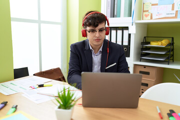 Non binary man business worker using laptop and headphones working at office